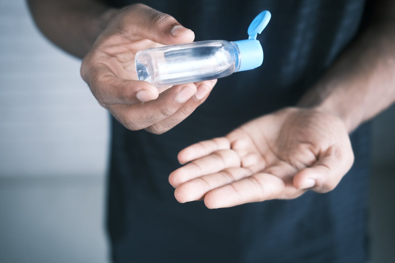 Hands using a hand sanitizer bottle to maintain hygiene and prevent germs.